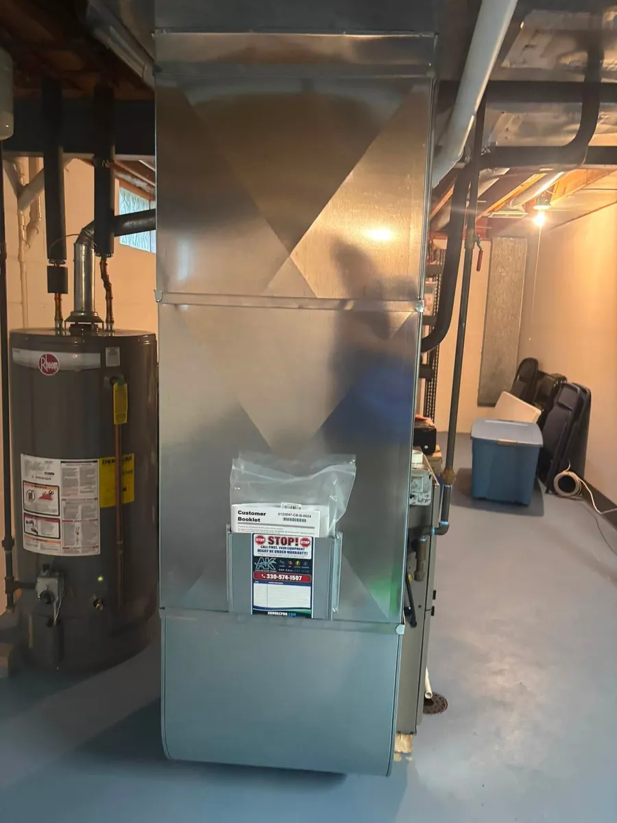 AK warranty sticker with the phone number (330) 574-1507 and the customer booklet, left on the ductwork of a new furnace